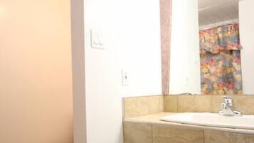 A bathroom with a toilet, sink, mirror, and a trash bin.