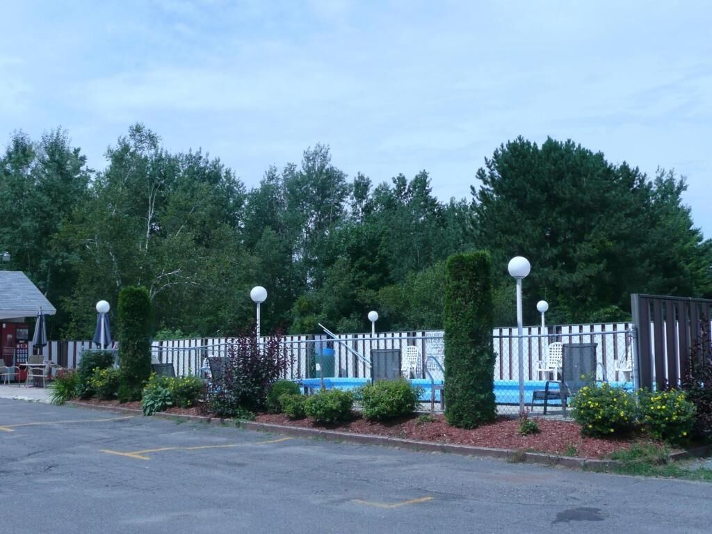 A fenced outdoor area with a building, a pool, and a row of lamp posts.