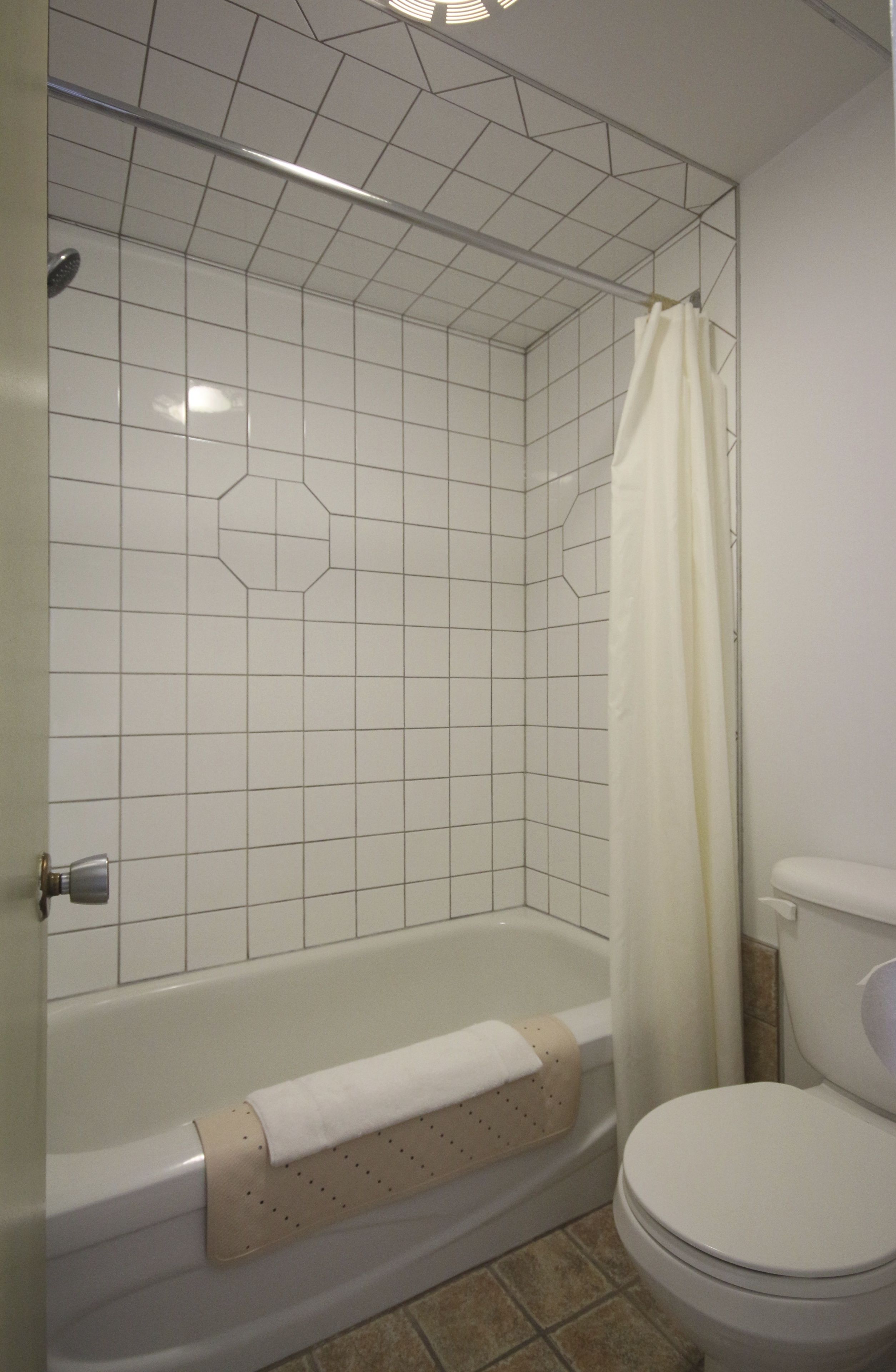 A bathroom with a bathtub, toilet, and shower curtain.