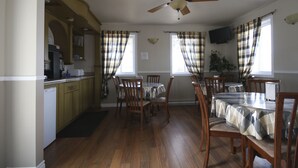 A dining area with a ceiling fan, checkered curtains, and wooden chairs and tables. - Motel Marie-Dan (Sainte-Eulalie)