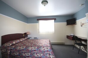 A bedroom with a bed, a desk, a chair, a television, and a window with blinds. - Motel Marie-Dan (Sainte-Eulalie)