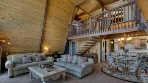 A spacious loft-style living area with high ceilings, a wooden staircase, and a balcony.