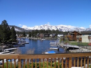 Une propriété au bord du lac, avec des bateaux amarrés, une terrasse en bois et une vue sur les montagnes en arrière-plan.