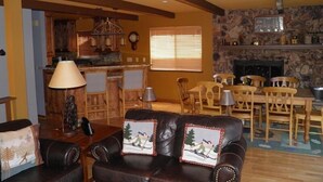 A cozy living room with a fireplace, wooden furniture, and a stone accent wall. - 584 Alpine Dr (South Lake Tahoe)