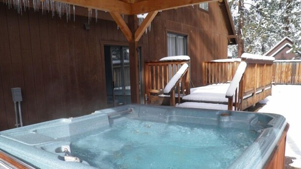 Een hottub in een houten buitenruimte, met een houten terras en een overdekte zithoek.