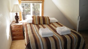 Een slaapkamer met een bed, nachtkastje, lamp en raam.
