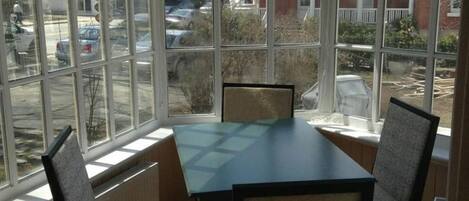 Un invernadero con mesa y sillas, ventanas amplias y vistas al exterior.