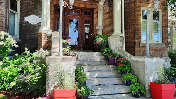 Een klassiek bakstenen gebouw met een bord waarop "Le 100 St-Laurent" en "Gîte Touristique Bed & Breakfast" staat.