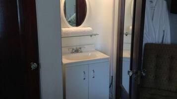 A small bathroom with a mirror, sink, and cabinet.