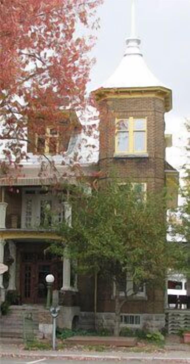 A Victorian-style building with a tower, brick facade, and a prominent front porch.