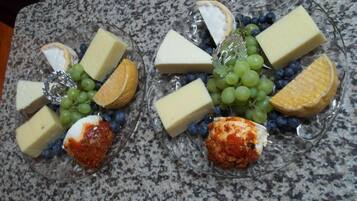 Two glass plates with cheese, grapes, and orange slices on a granite countertop.