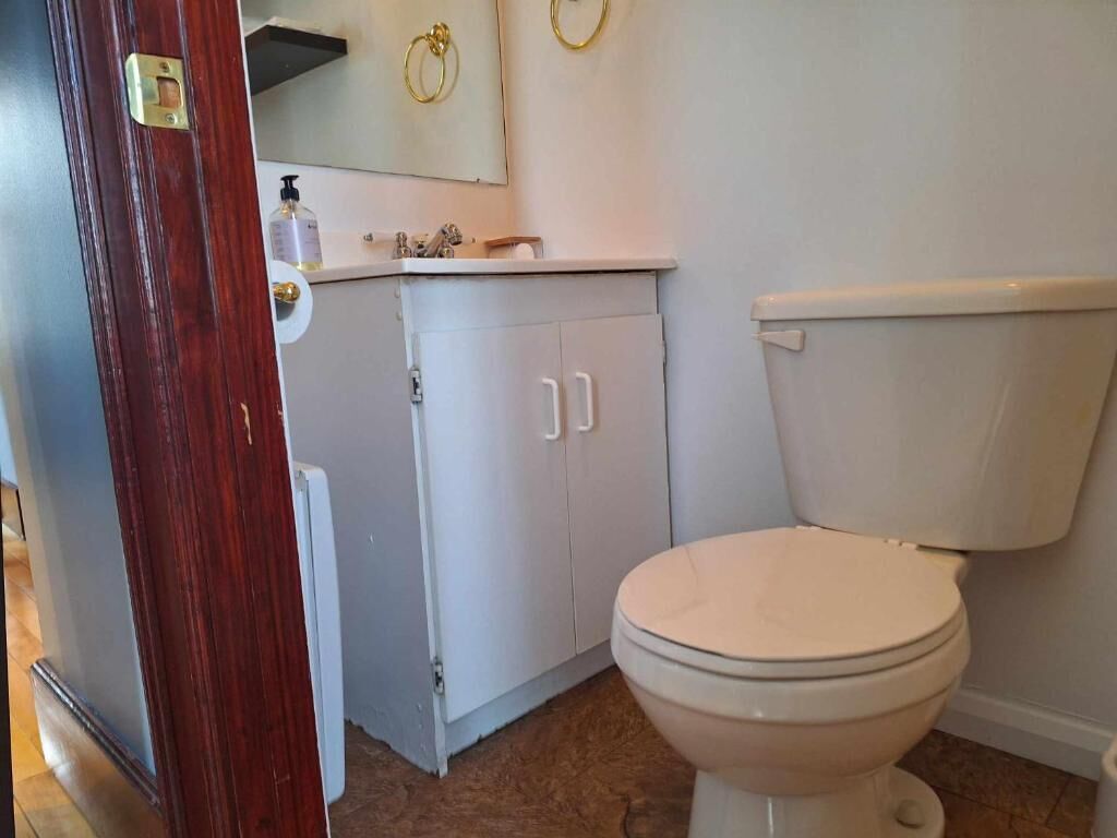 A bathroom with a toilet, a sink, and a cabinet.