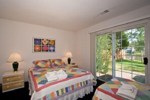 Un dormitorio con una cama grande, una cama más pequeña y una ventana con vista a zonas verdes.