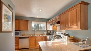 Cucina con mobili in legno, un piano di lavoro in granito ed elettrodomestici moderni.