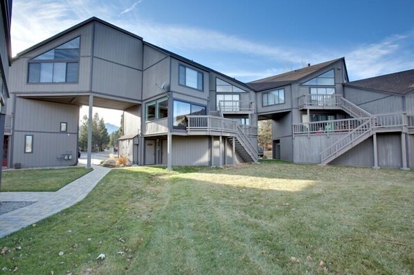 A modern multi-story building with a flat roof, large windows, and a covered outdoor area with stairs.