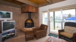 A cozy living room with a fireplace, leather chairs, a TV, and a view of the outdoors.