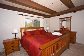 A bedroom with a wooden bed, nightstands, a dresser, and a mirror.