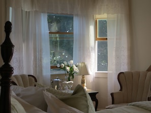 A bedroom with a large window, a bedside table with a lamp, and a chair. - Atlantic Ark Inn (Boothbay Harbor)