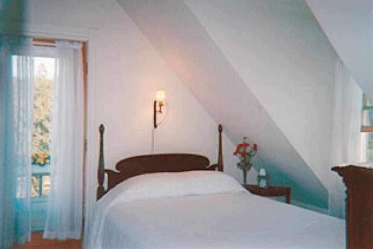 A bedroom with a wooden bed, a nightstand, and a wall-mounted light fixture.