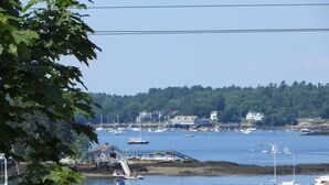 A marina with boats, a dock, and a forested hill in the background. - Atlantic Ark Inn (Boothbay Harbor)