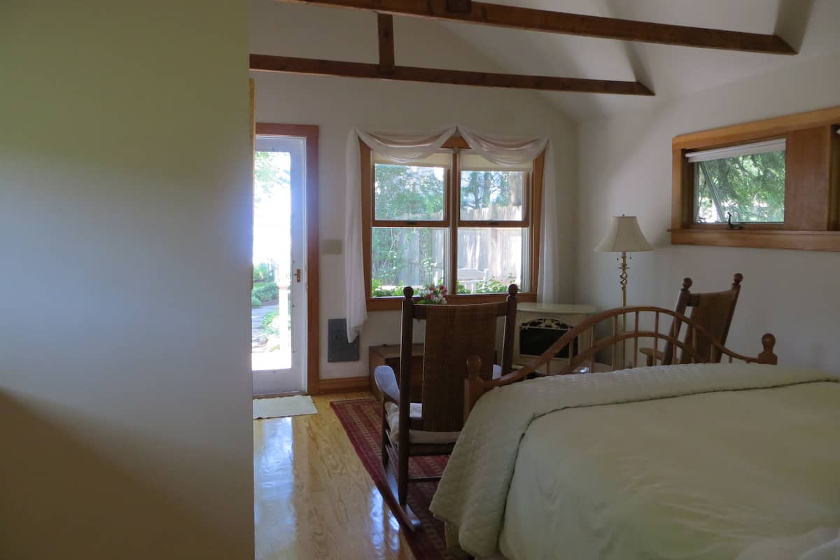 A bedroom with a bed, a chair, a table, and a window.