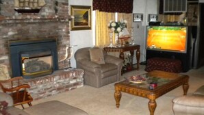 A living room with a fireplace, leather sofas, a coffee table, and a television. - 528 Tahoe Keys Blvd (South Lake Tahoe)