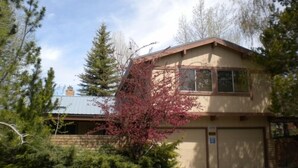 A two-story house with a garage, surrounded by trees and a grassy yard. - 528 Tahoe Keys Blvd (South Lake Tahoe)