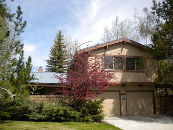 A two-story house with a garage, surrounded by trees and a grassy yard.