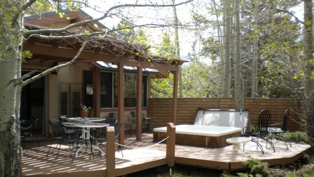 A wooden deck with outdoor furniture, including a table and chairs, and a hot tub. - 528 Tahoe Keys Blvd (South Lake Tahoe)