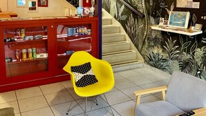 A cozy bar area with a staircase, a yellow chair, and a grey sofa. - Kera Smart Hostel (São Paulo)