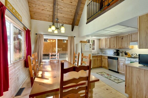 A wooden interior with a dining table, chairs, a kitchen with wooden cabinets, and a staircase. - 2275 Silver Tip (South Lake Tahoe)