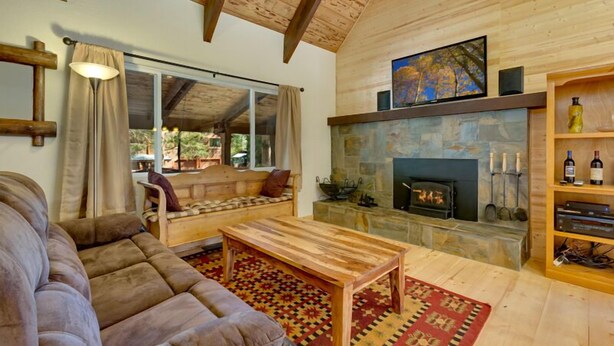 Una sala de estar acogedora con chimenea, muebles de madera y un gran ventanal con vistas a un jardín.