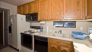 A kitchen with wooden cabinets, a microwave, a refrigerator, an oven, and a dishwasher.