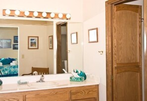 A bathroom with a vanity, mirror, and wooden door. - 2485 Tepee Ct. (South Lake Tahoe)