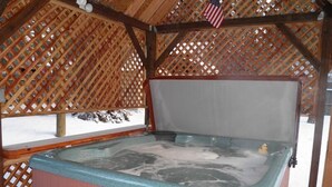A hot tub with a wooden lattice structure overhead and an American flag.