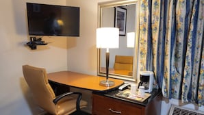 A hotel room with a desk, chair, TV, lamp, mirror, and a coffee maker. - Star Inn (Barstow)