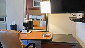 A hotel room with a desk, chair, television, and a bed with a headboard. - Star Inn (Barstow)