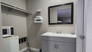 A modern bathroom with a white sink, mirror, and a microwave on the left. - Star Inn (Barstow)