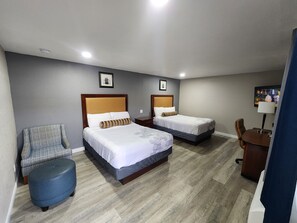 A hotel room with two beds, a chair, a desk, and a TV. - Star Inn (Barstow)