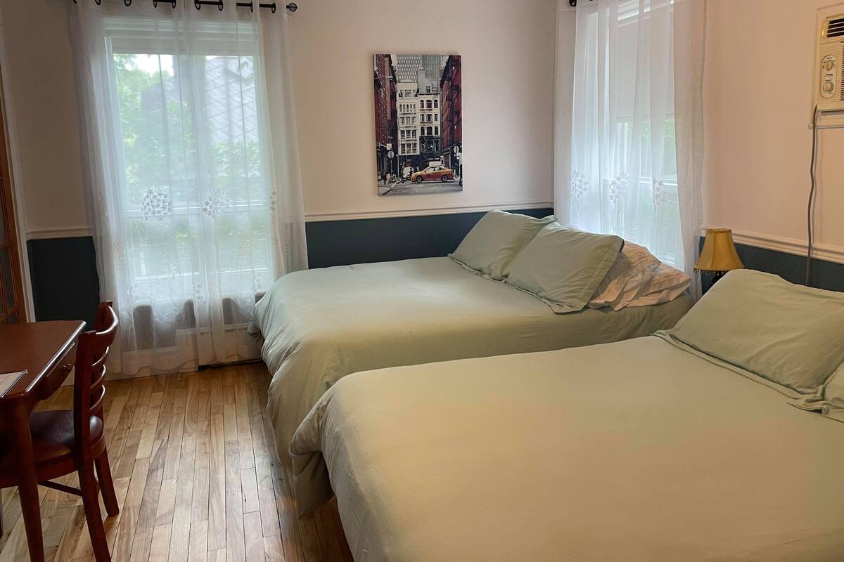 Una habitación con dos camas, un escritorio de madera y una silla.
