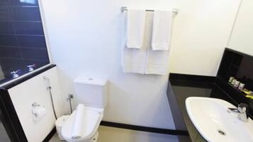 Un baño pequeño y moderno con inodoro, lavamanos y toallero.