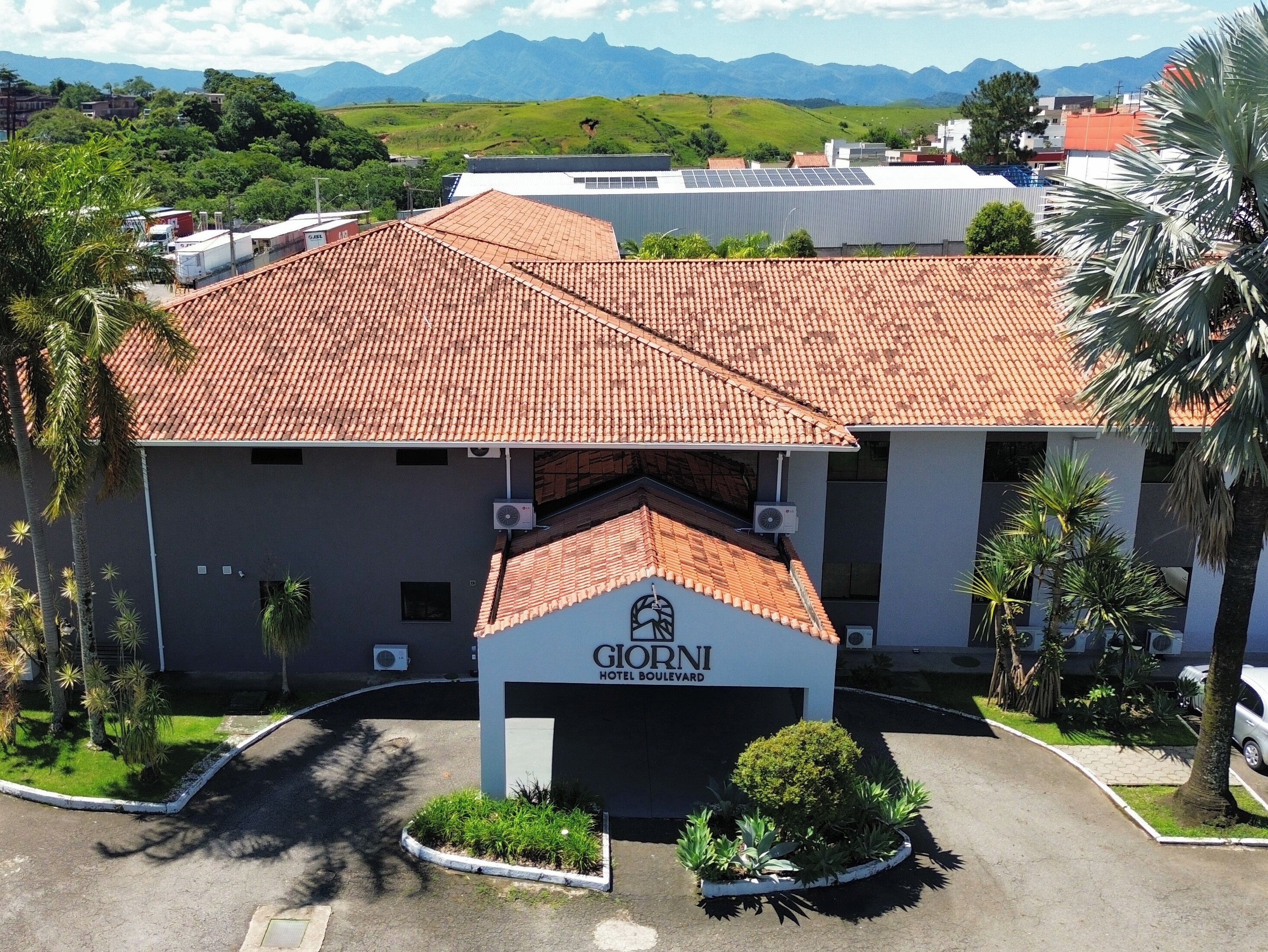 Un hotel con techo de tejas rojas, un letrero que dice 'Giorni Hotel Boulevard' y un área de entrada ajardinada.