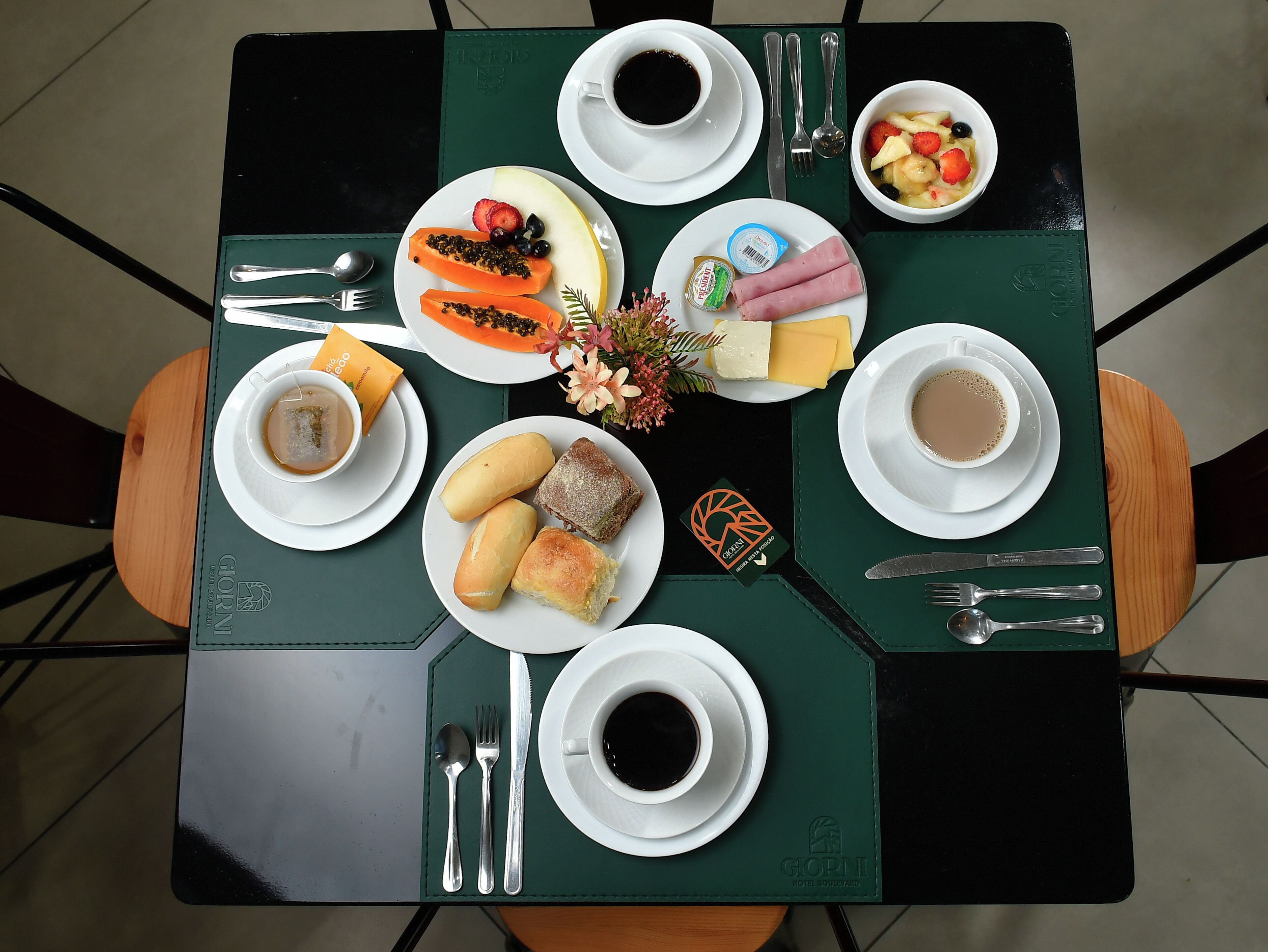 A dining table with plates of food, cups of coffee, and cutlery.