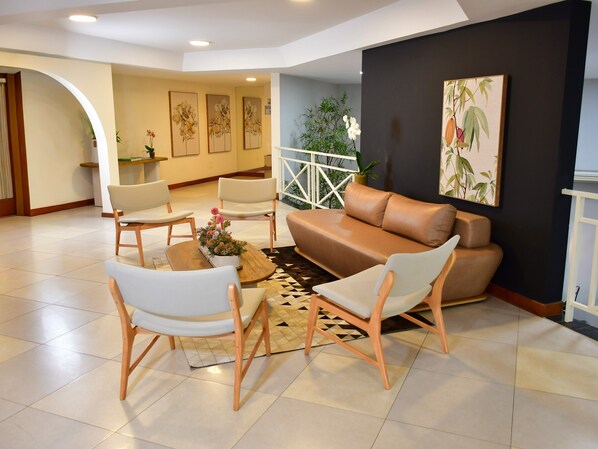 Una sala de estar moderna con un sofá, sillas, una mesa de centro y obras de arte en las paredes.