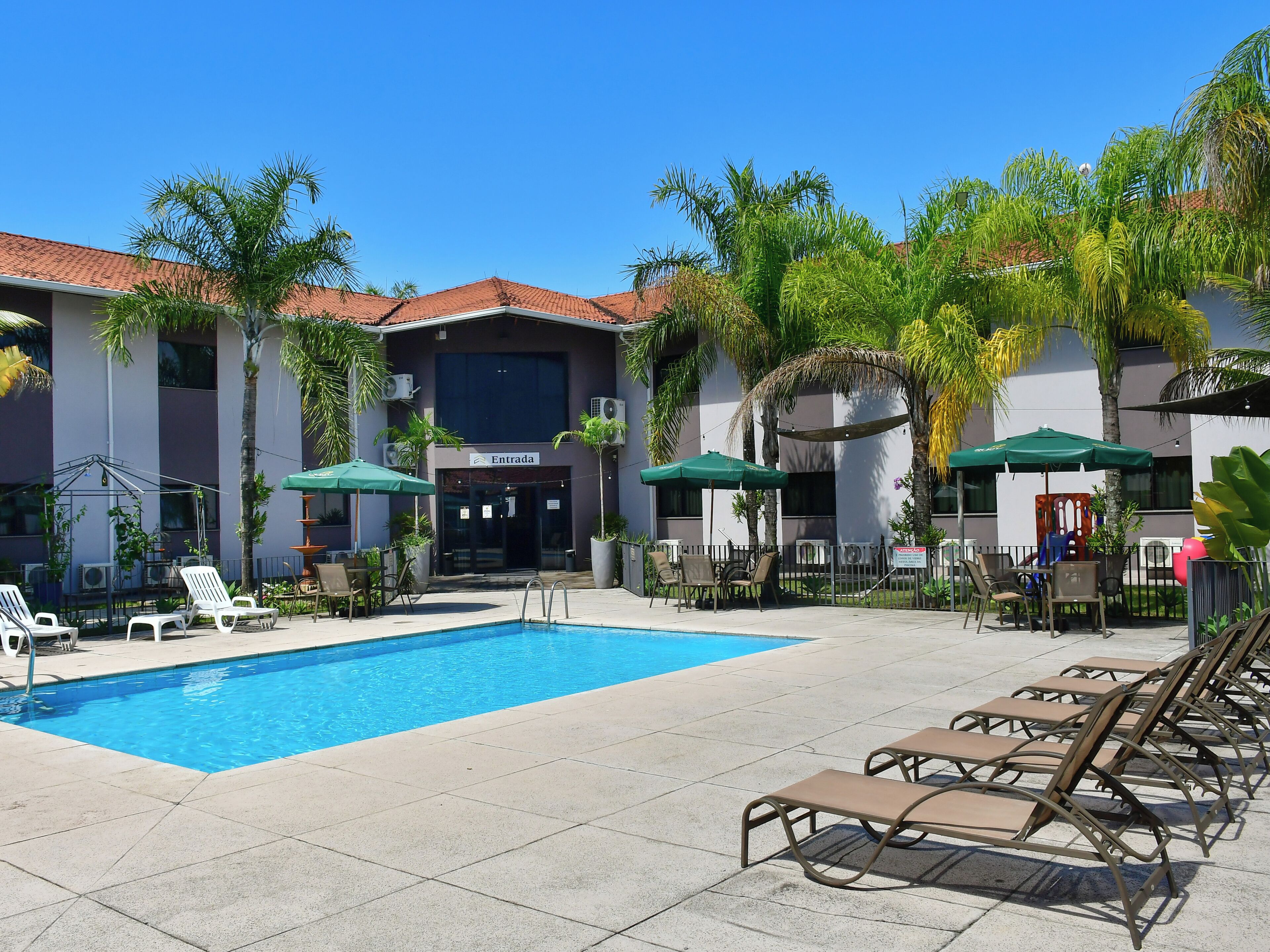A pool area with lounge chairs, umbrellas, and a building labeled 'Entrada'.