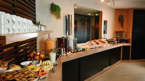 A buffet with various food items, a coffee station, and a mirror reflecting the room. -  Giorni Hotel Boulevard (Resende)