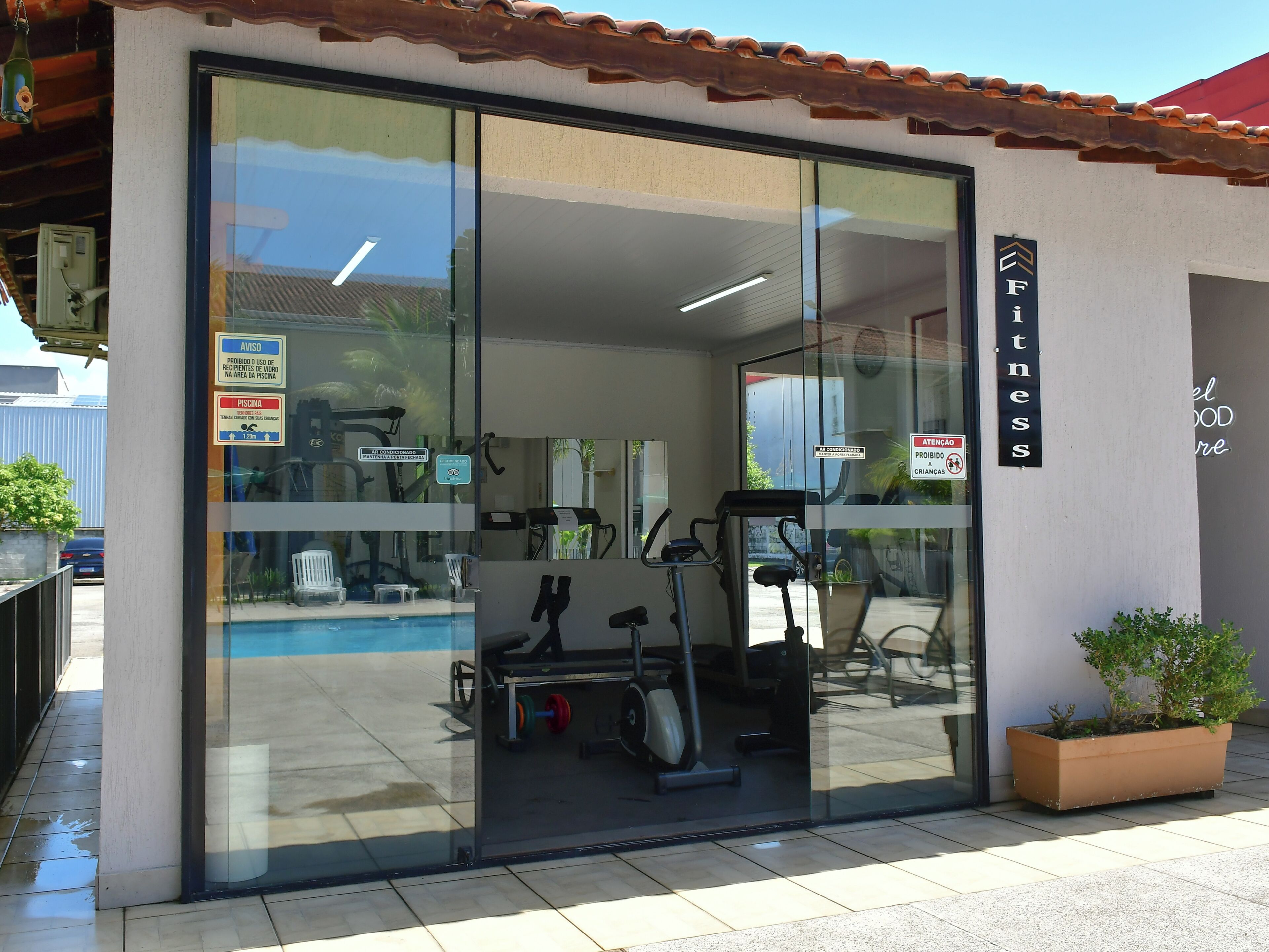 A fitness center with exercise equipment, a swimming pool, and a sign indicating no children allowed.