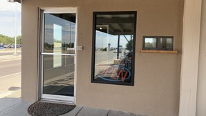 A storefront with a glass door, a 'No Smoking' sign, and a 'OPEN' sign on the window. - Mayo Inn (Roswell)