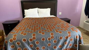 Ein Bett mit einem gemusterten Überwurf, zwei Nachttische und ein an der Wand befestigter Heizkörper.