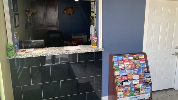 A reception area with a marble counter, a desk, and a bulletin board displaying various travel brochures. - Mayo Inn (Roswell)